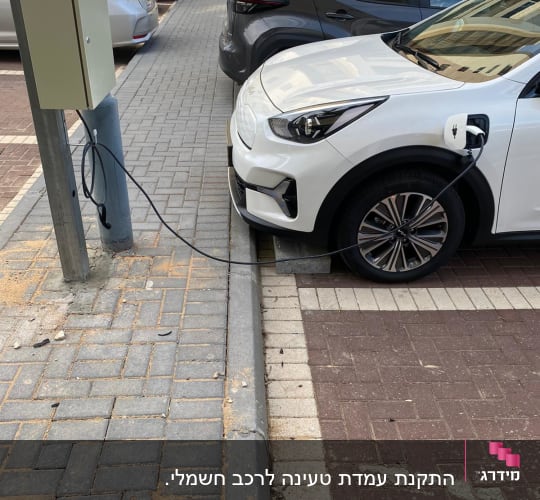 רכב חשמלי מחובר לעמדת טעינה ברחוב